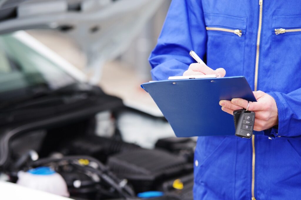 Mechaniker bei der Durchsicht eines Autos, TÜV-Untersuchung