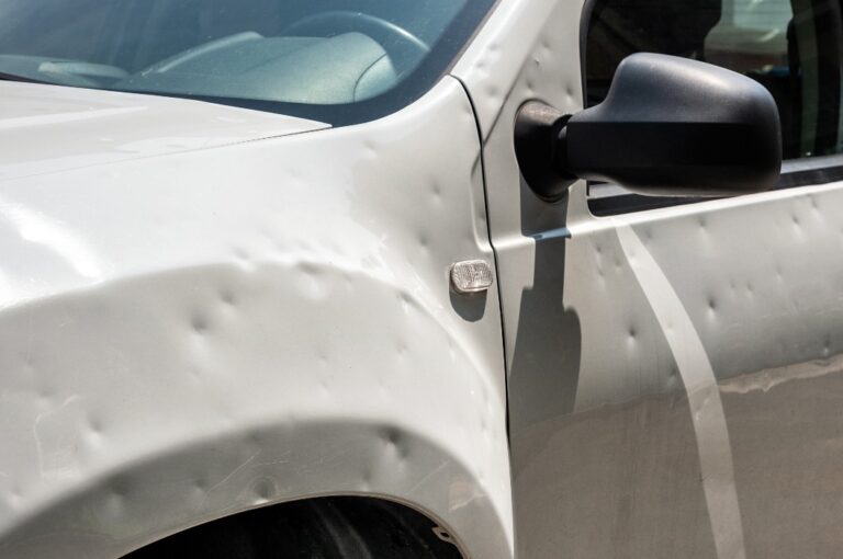 Verbeultes weißes Auto nach Hagelsturm auf der Straße geparkt